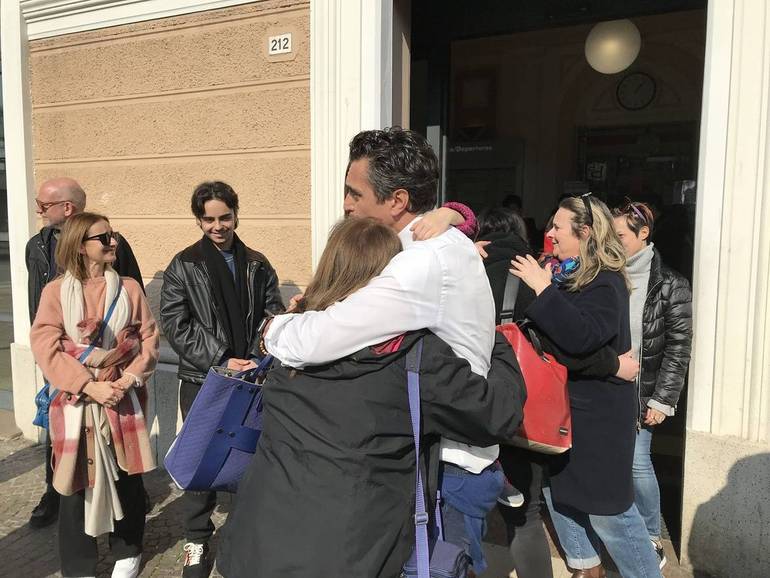 Il padre di Antonio, Andrea, ieri davanti alla stazione, mentre abbraccia i passanti, studenti e viaggiatori